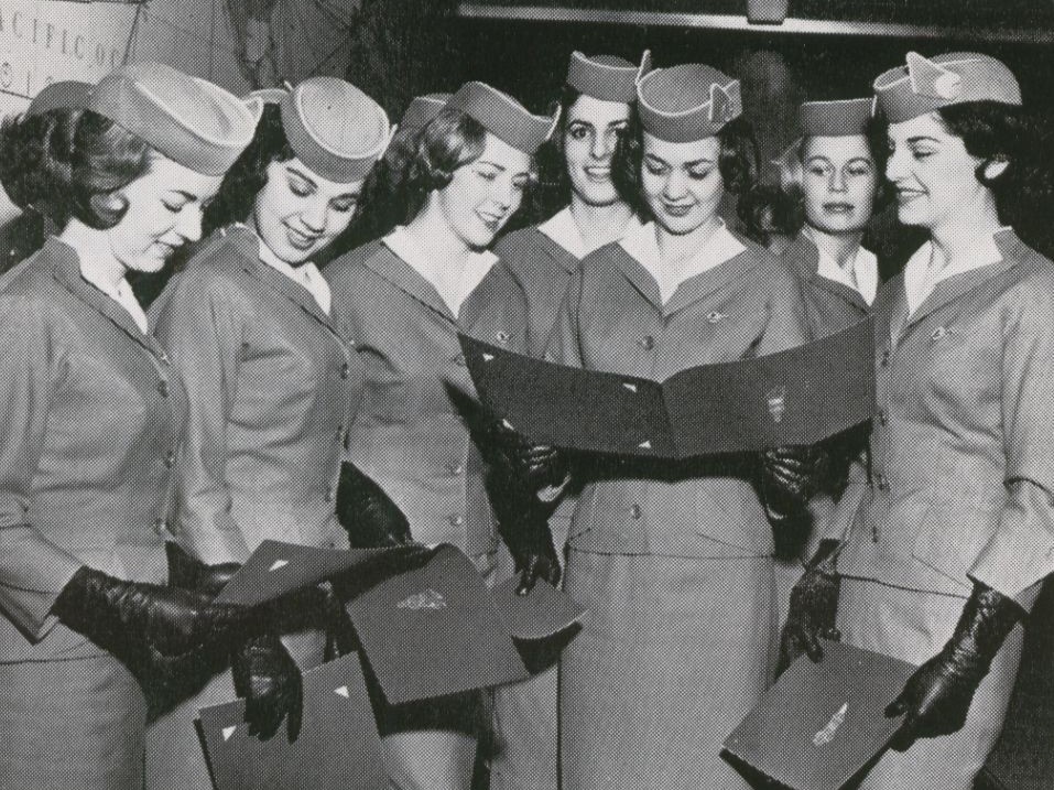 1959 A group of newly hired stewardesses review their diplomas on graduation day.